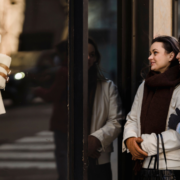 Two women enjoying window shopping in a stylish urban area, reflecting joy and friendship.