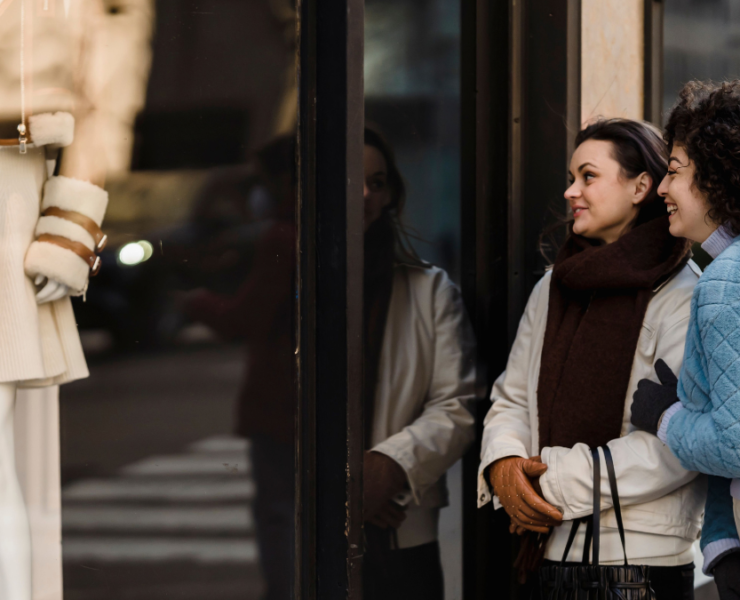 Two women enjoying window shopping in a stylish urban area, reflecting joy and friendship.